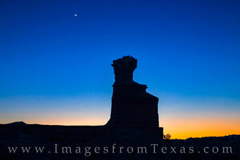 The Lighthouse hoodoo rests under a fading crescent moon in Palo Duro Canyon.