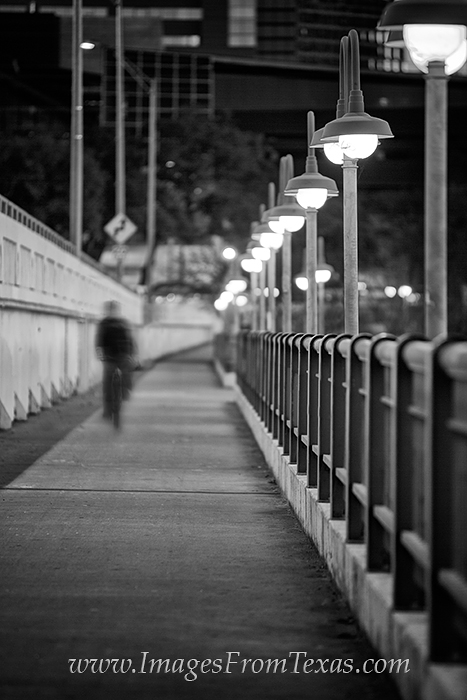 Along the side of one of Austin's main bridges, a pedestrian heads to work on his bicycle in the early hours of the day.