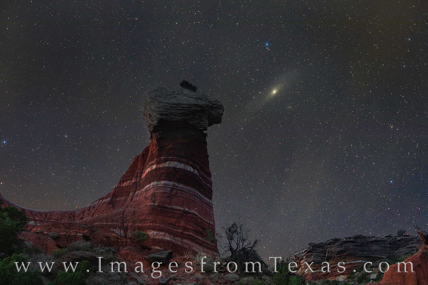 The Andromeda Galaxy, also known as Messier 31 (M31) rests in the night sky over Red Star Hoodoo in Palo Duro Canyon. This image...