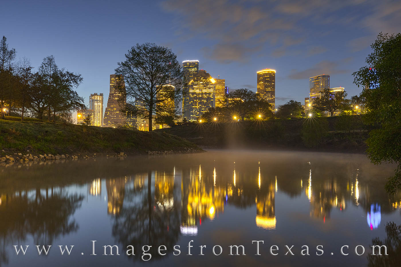 With a light fog rising from the still waterway of Buffalo Bayou, the reflection of the Houston skyline appears clear and colorful...