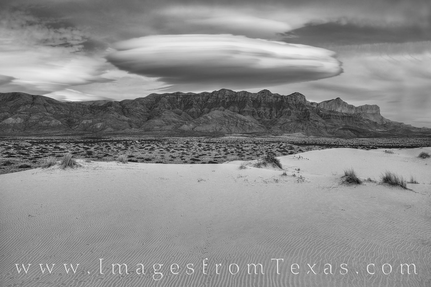 This black and white image from the Guadalupe Mountains’ Salt Basin Dunes shows a rare lenticular cloud as it hovers like a...