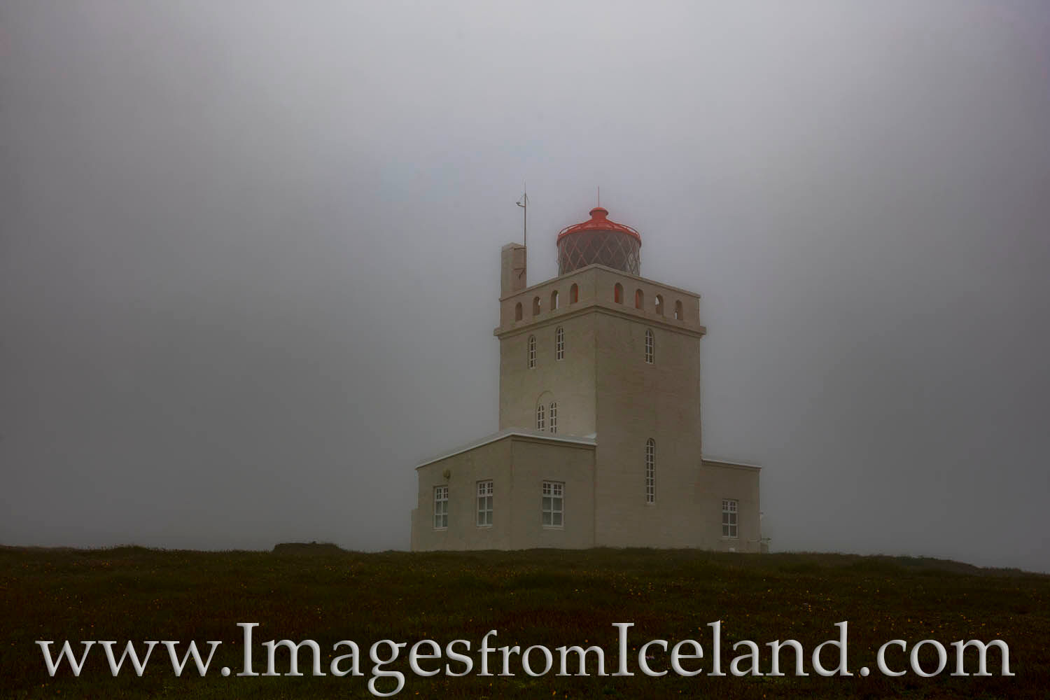 The Dyrhólaey Lighthouse near Vik hides under a dense fog on a summer afternoon.
