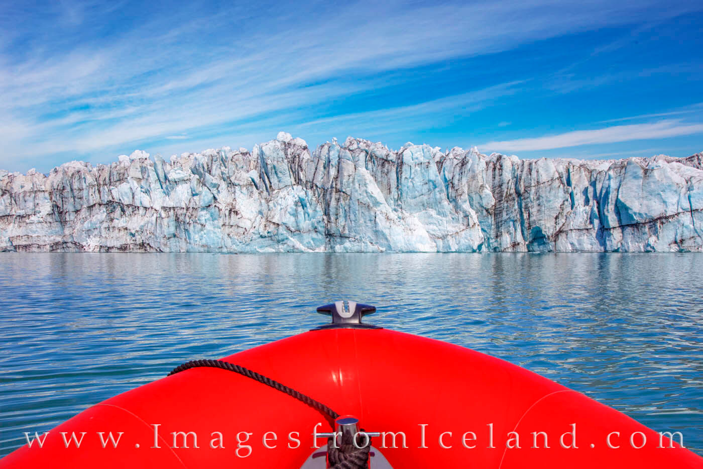 Breiðamerkurjökull Glacier looms in front of our tiny Zodiac boat on a cold summer morning in Jökulsárlón Lagoon. From this...