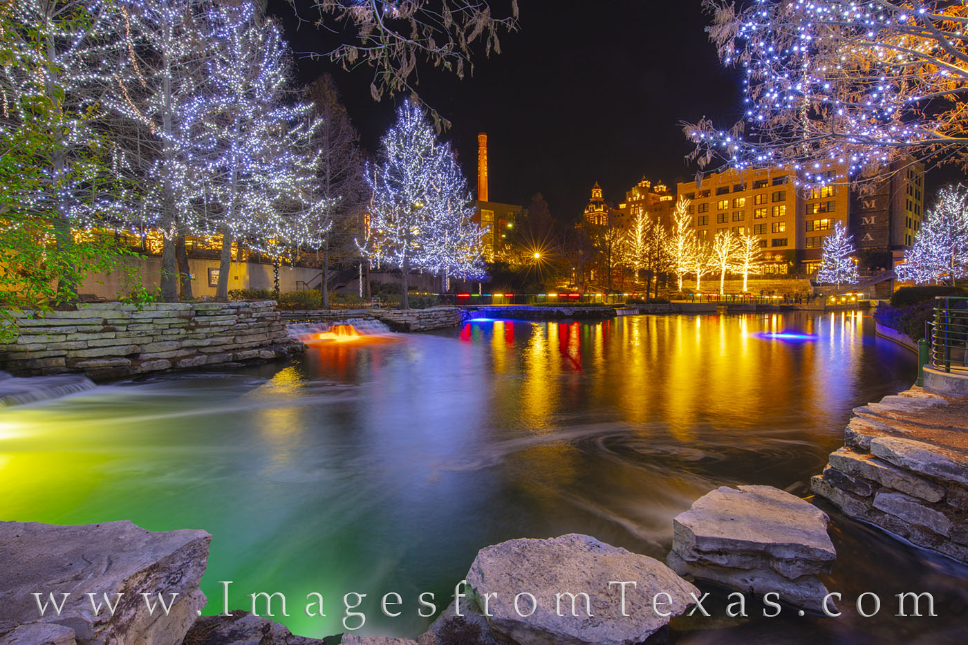 Lights of white and gold and blue light up the trees while underwater lighting of green and orange add color to this portion...