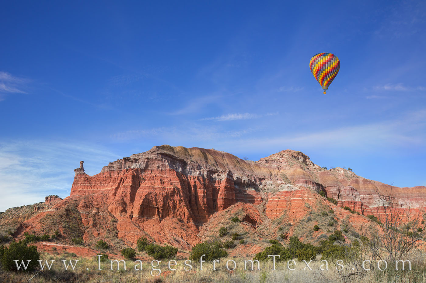 A hot air balloon floats over the red sandstone and hoodoos of Palo Duro Canyon in the Texas panhandle. This image was made on...