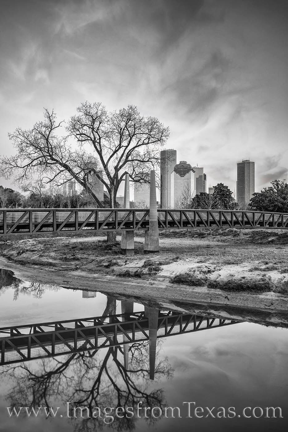 A cold winter evening embraces downtown Houston in this black and white photograph. Buffalo Bayou's waters are perfectly still...