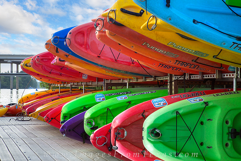 Ready for action, these colorful canoes await the next customer at a dock on the waters of Lady Bird Lake. On a warm August morning...