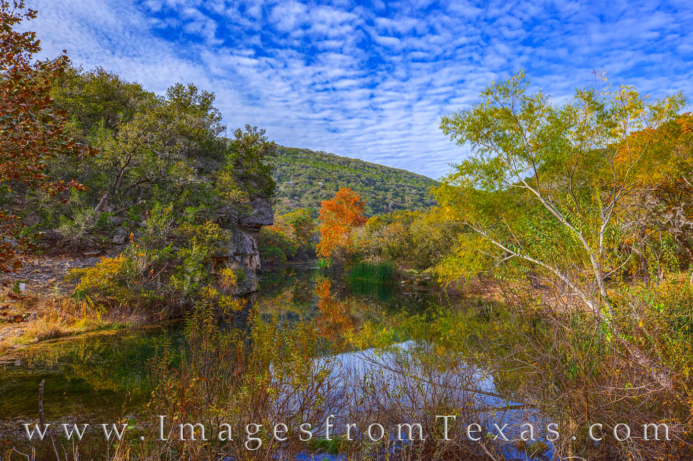 A small pond on the East Trail in Lost Maples rests quietly under a beautiful sky while surrounded by the changing Autumn colors...
