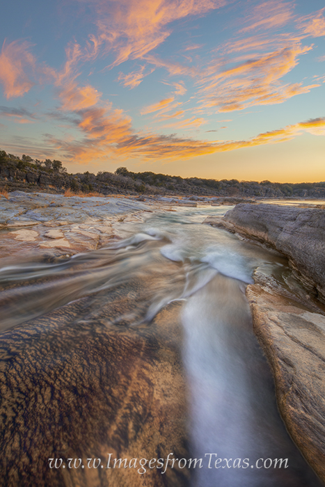 In the soft glow and half-light of early morning, the clean water of the Pedernales River flows through the Texas Hill Country...