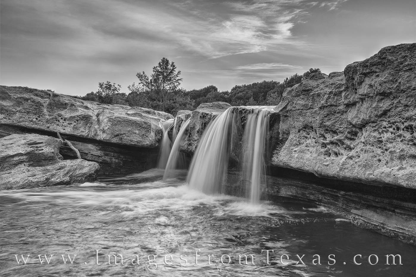 From the Lower Falls in Mckinney Falls State Park, this black and white photograph shows the gentle cascade on a warm summer...
