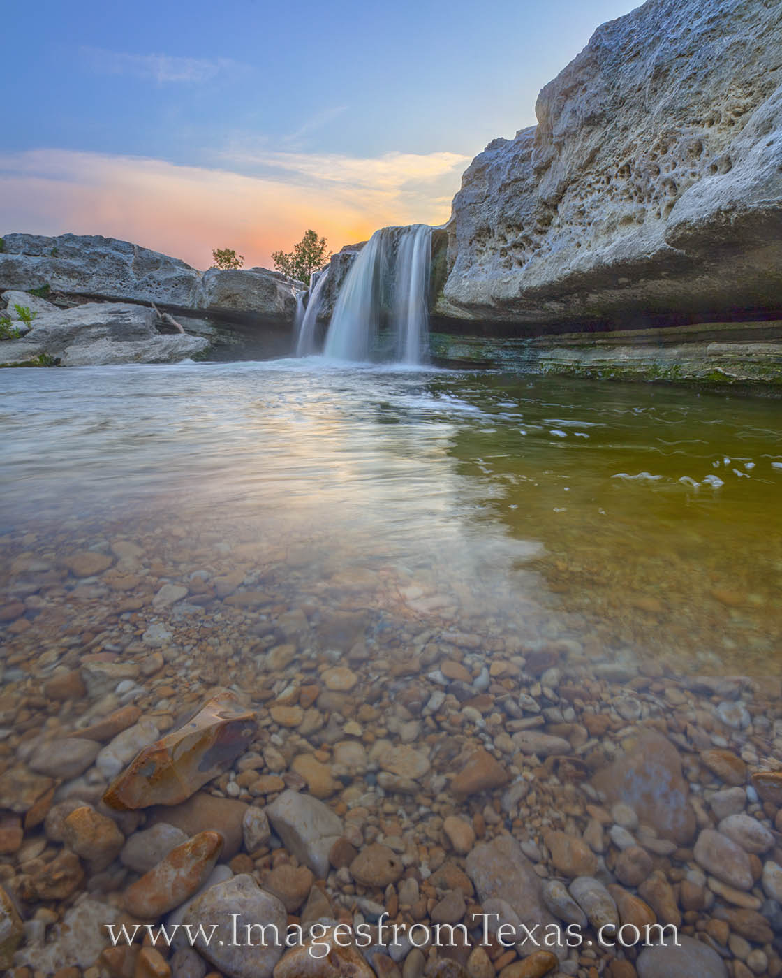 The clear water from Onion Creek pours over the small cascade of Lower Falls in McKinney Falls State Park. This nature sanctuary...