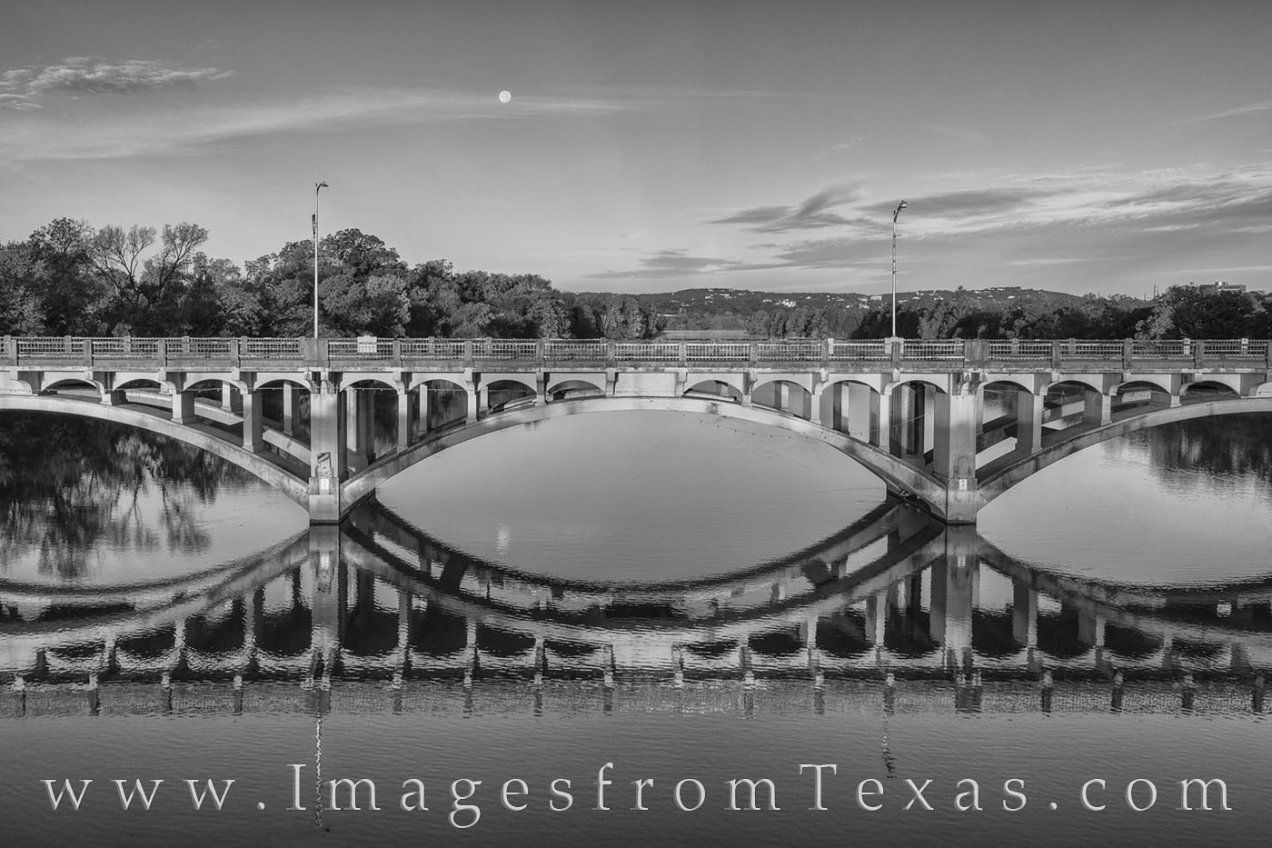 This black and white image from Austin, Texas, shows the curves and architecture of Lamar Bridge. Ladybird Lake flows beneath...
