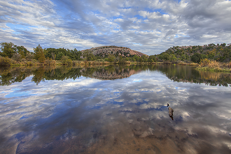On a calm late November afternoon, clouds drift over Enchnated Rock. In the foreground, Moss Lake offers the reflections of blue...