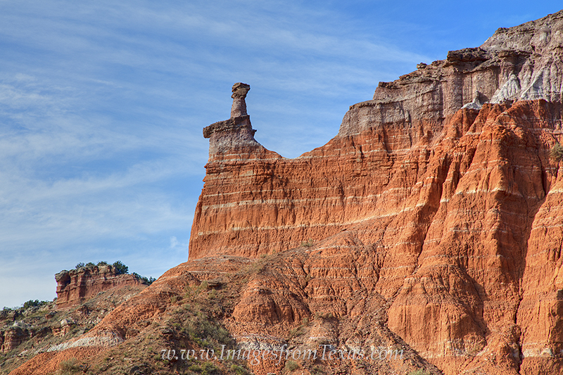 In the morning just after sunrise, a hoodoo and the surrounding layers of rock at Palo Duro Canyon glow in the orange sunlight...