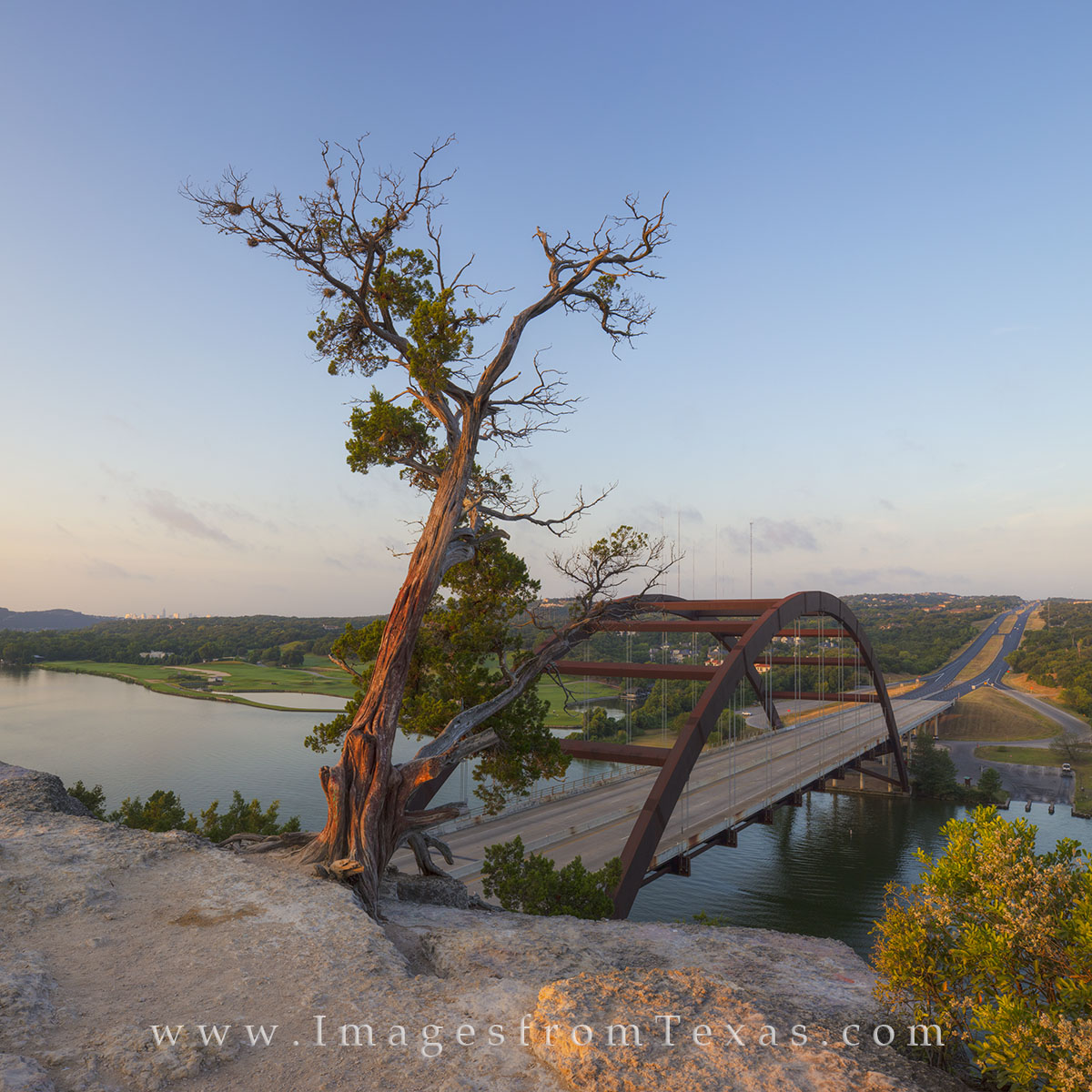 From atop the famous limestone cliffs overlooking the Colorado River, this image shows the Pennybacker Bridge, also known as...