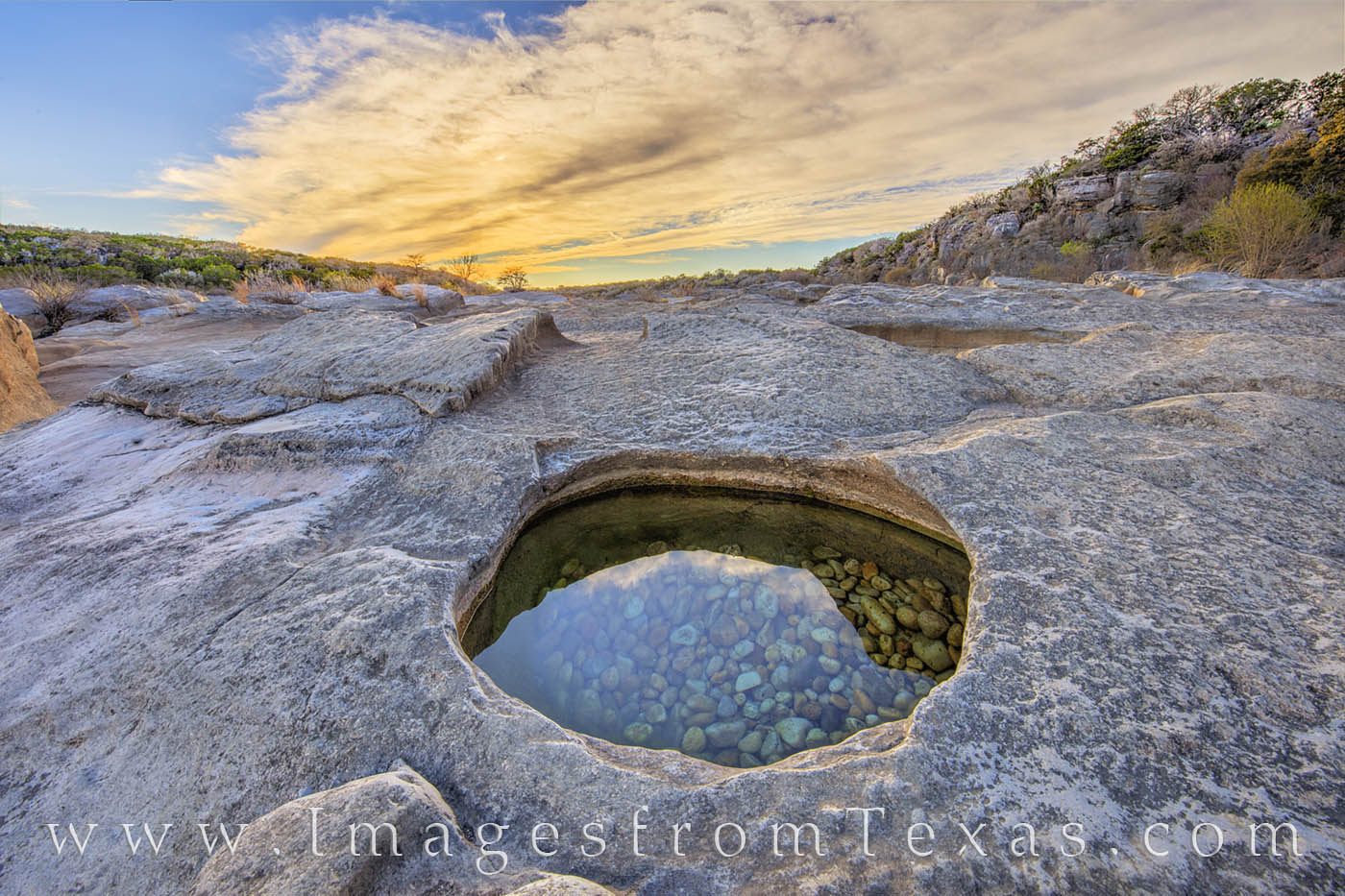 A small rock pool at Pedernales Falls State Park holds colorful, smooth pebbles in its clear water.