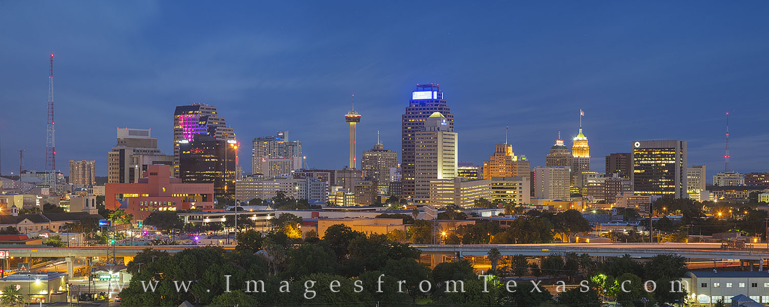 Evening falls across the San Antonio skyline on a June evening. In the foreground, Interstate 35 runs north and south, and colors...