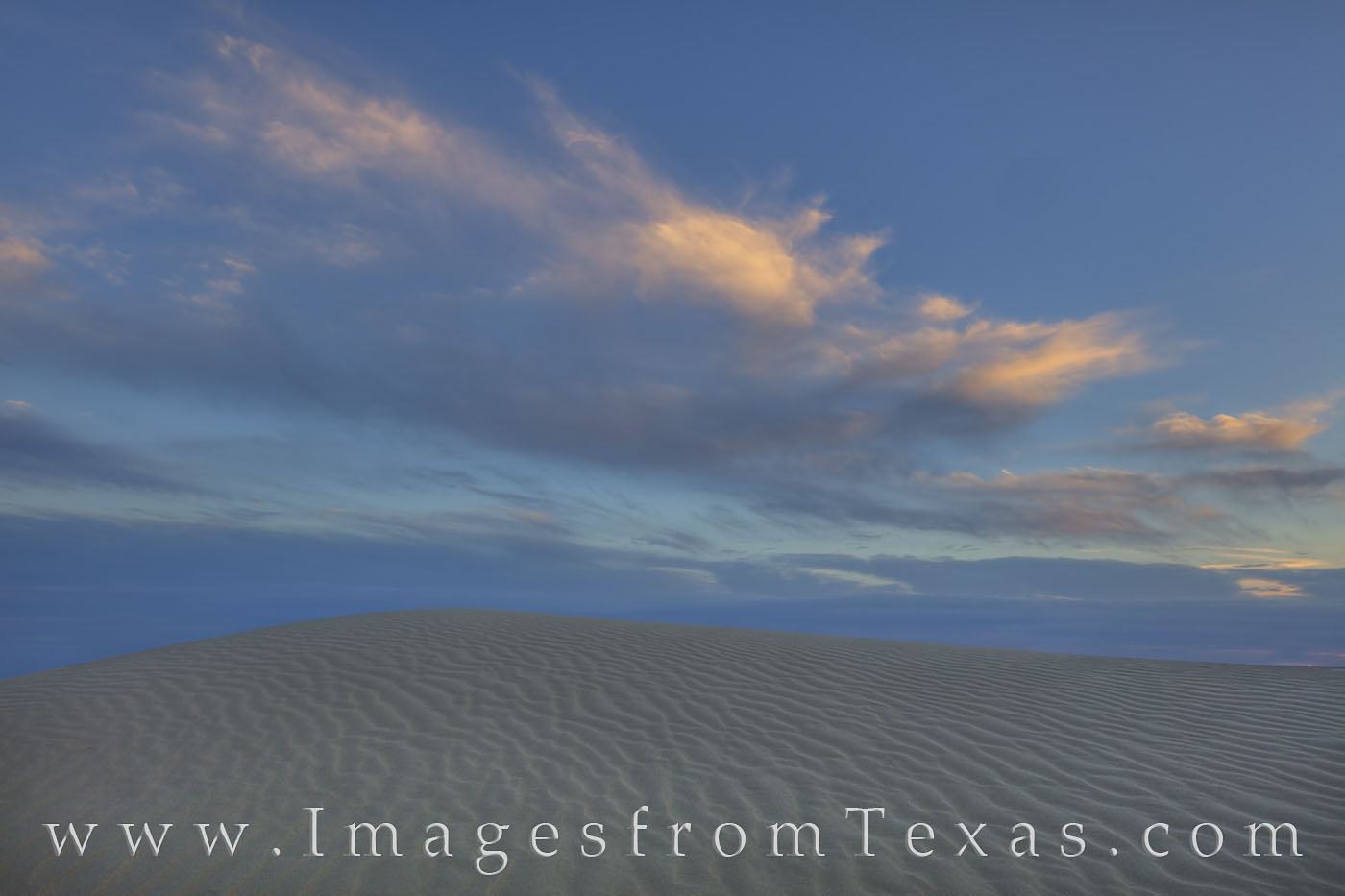 Clouds show the last colors of a Spring day as they drift across the sand dunes of Monahans Sandhills State Park This sandy oasis...