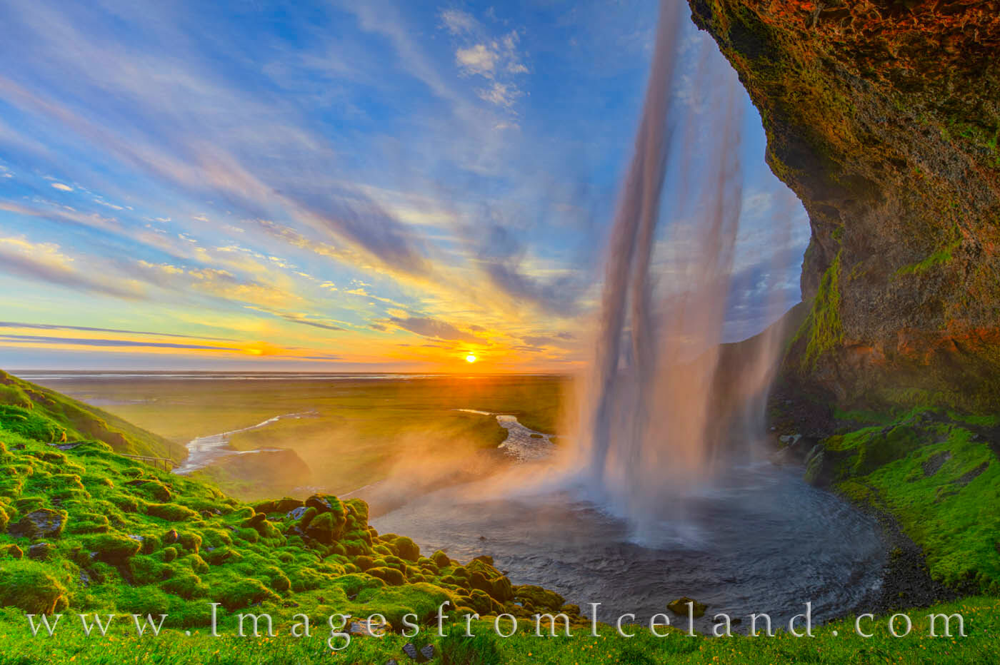 The midnight glow of the summer sun spreads its warm light across the falling water of Seljalandsfoss, one of the most beautiful...