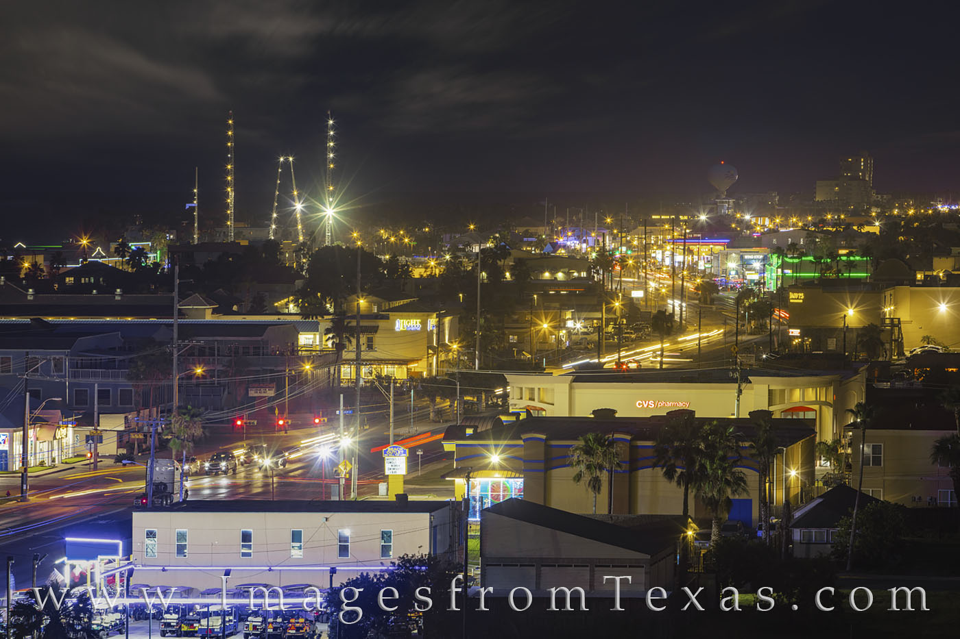 This nighttime photograph looks south down Padre Blvd. The long exposure shows the winding of red taillights and white headlights...