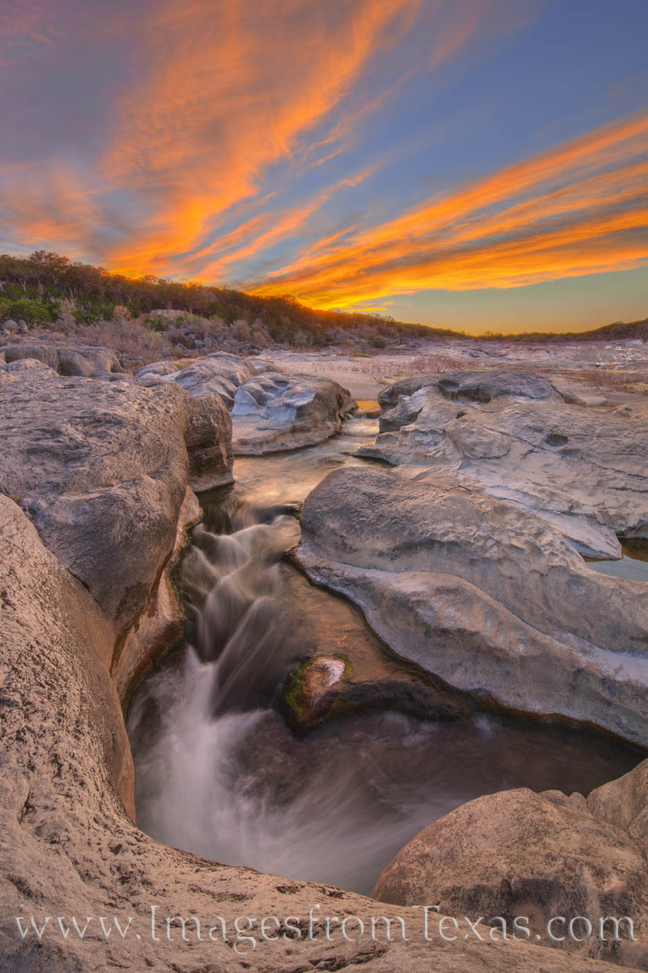 Flowing fast and clean, the Pedernales River rushes through a small limestone canyon at Pedernales Falls State Park on a beautiful...