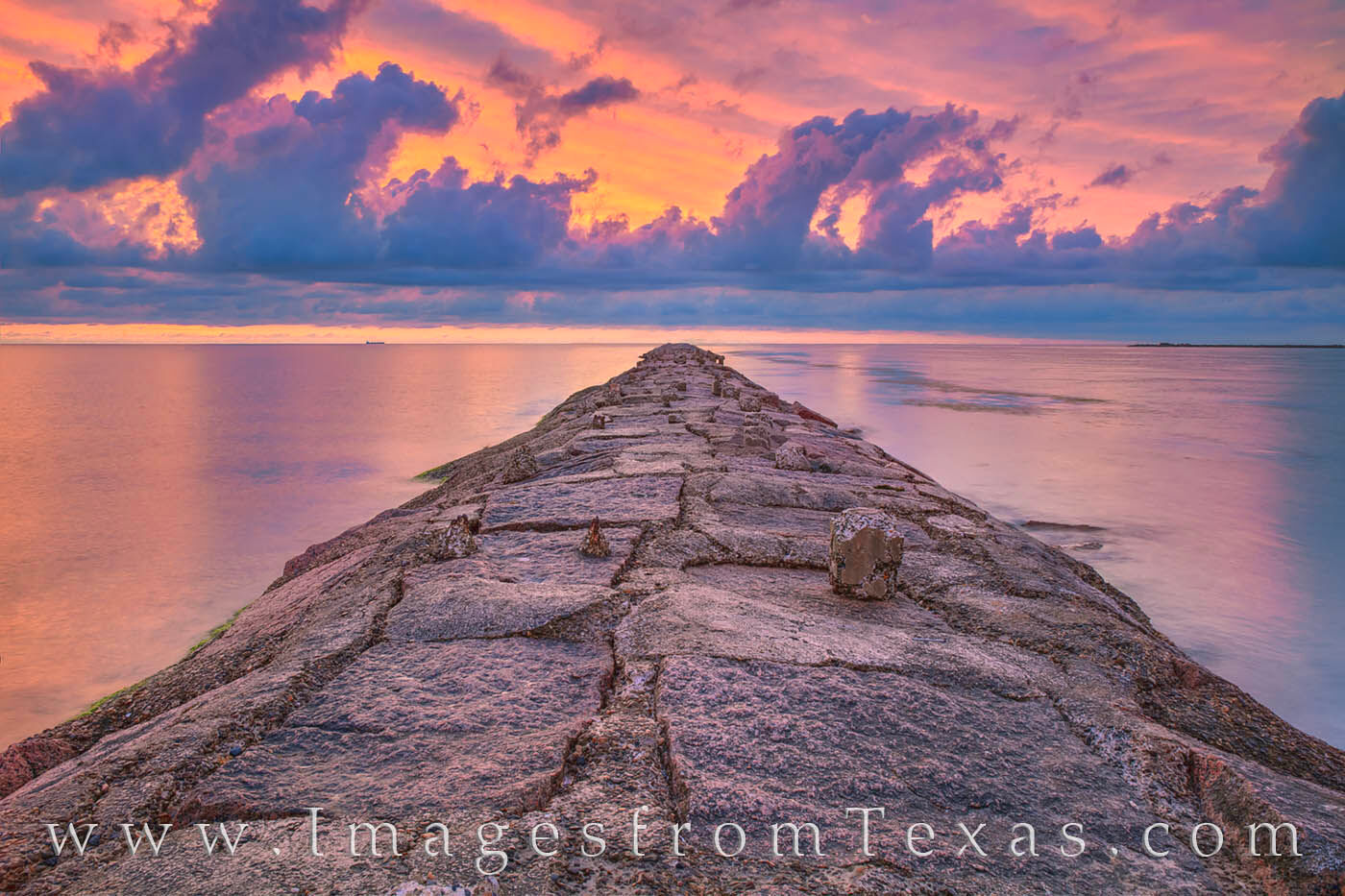 The jetty near Isla Blanca reaches out into the warm gulf waters from South Padre Island. The high clouds let up in pastel pink...