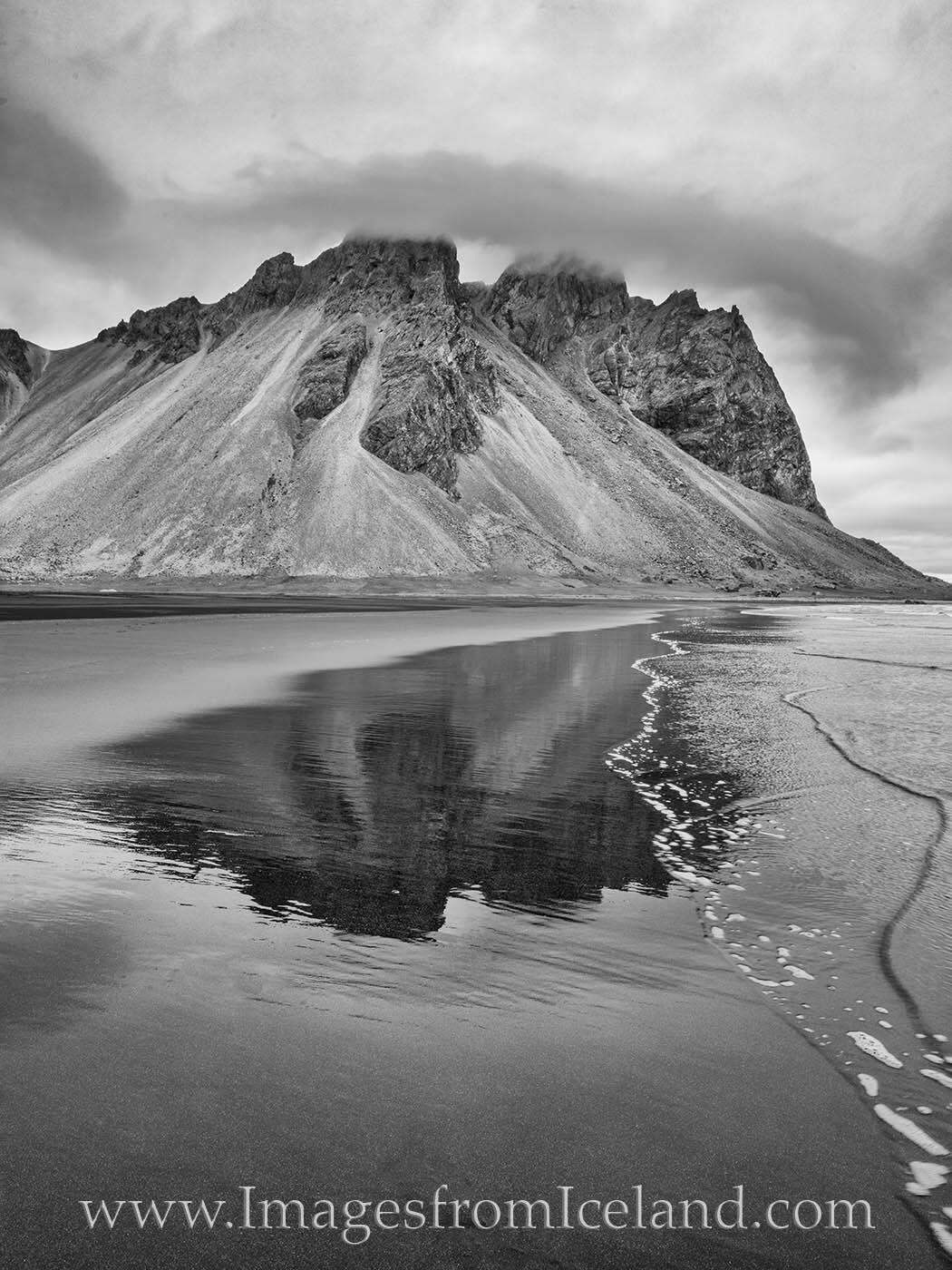 Clouds encircle the rocky heights of the iconic Vestrahorn Mountain. This black and while image shows the reflection of this...