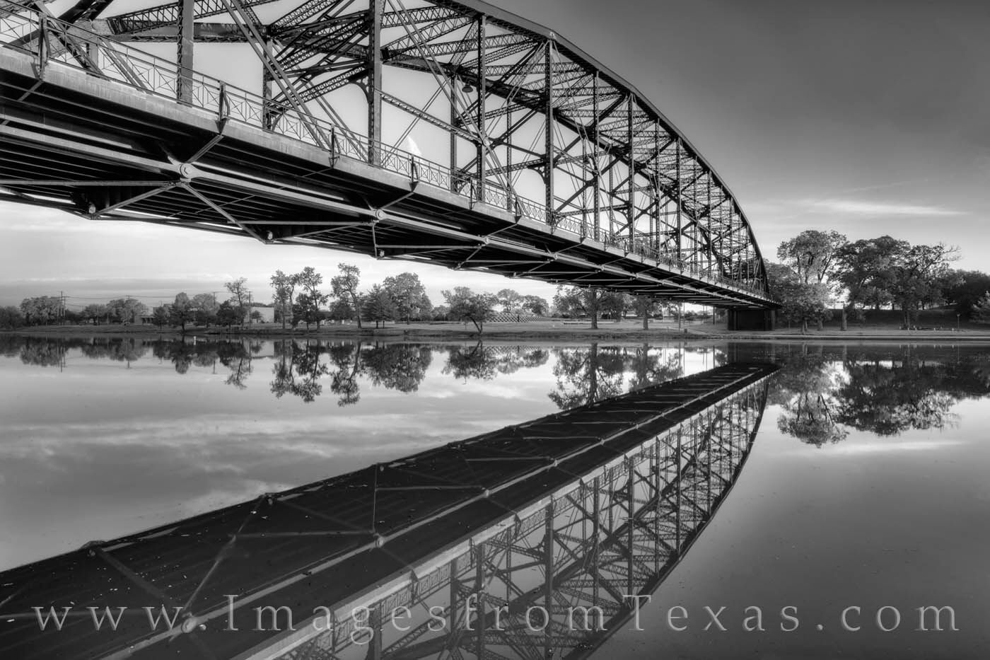 From the east end of the Waco Riverwalk, the Washington Avenue Bridge and its reflection in the Brazos River are pictured here...
